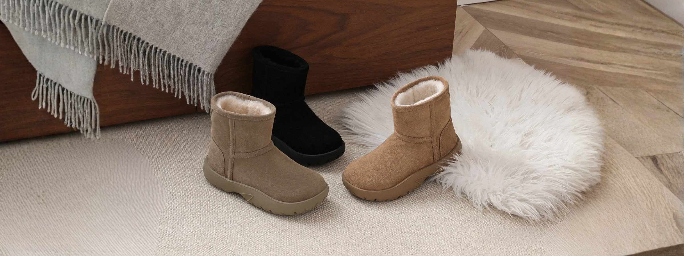 Three pairs of short UGG boots in chestnut, sand, and black displayed indoors on a soft rug and wooden floor – Shop genuine Australian sheepskin short Ugg boots from Peroz Australia.