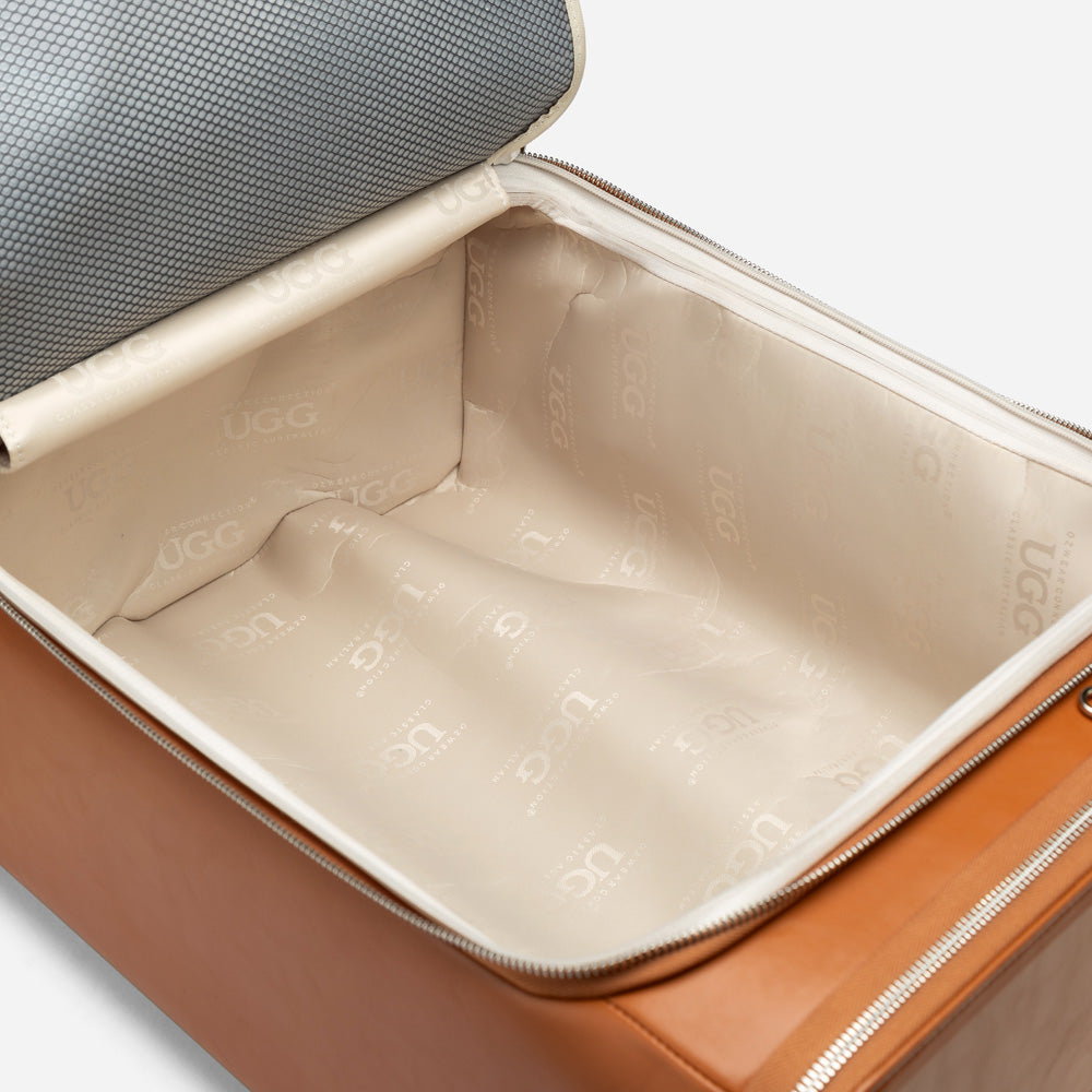 Open suitcase with beige interior and UGG branding on a light gray background