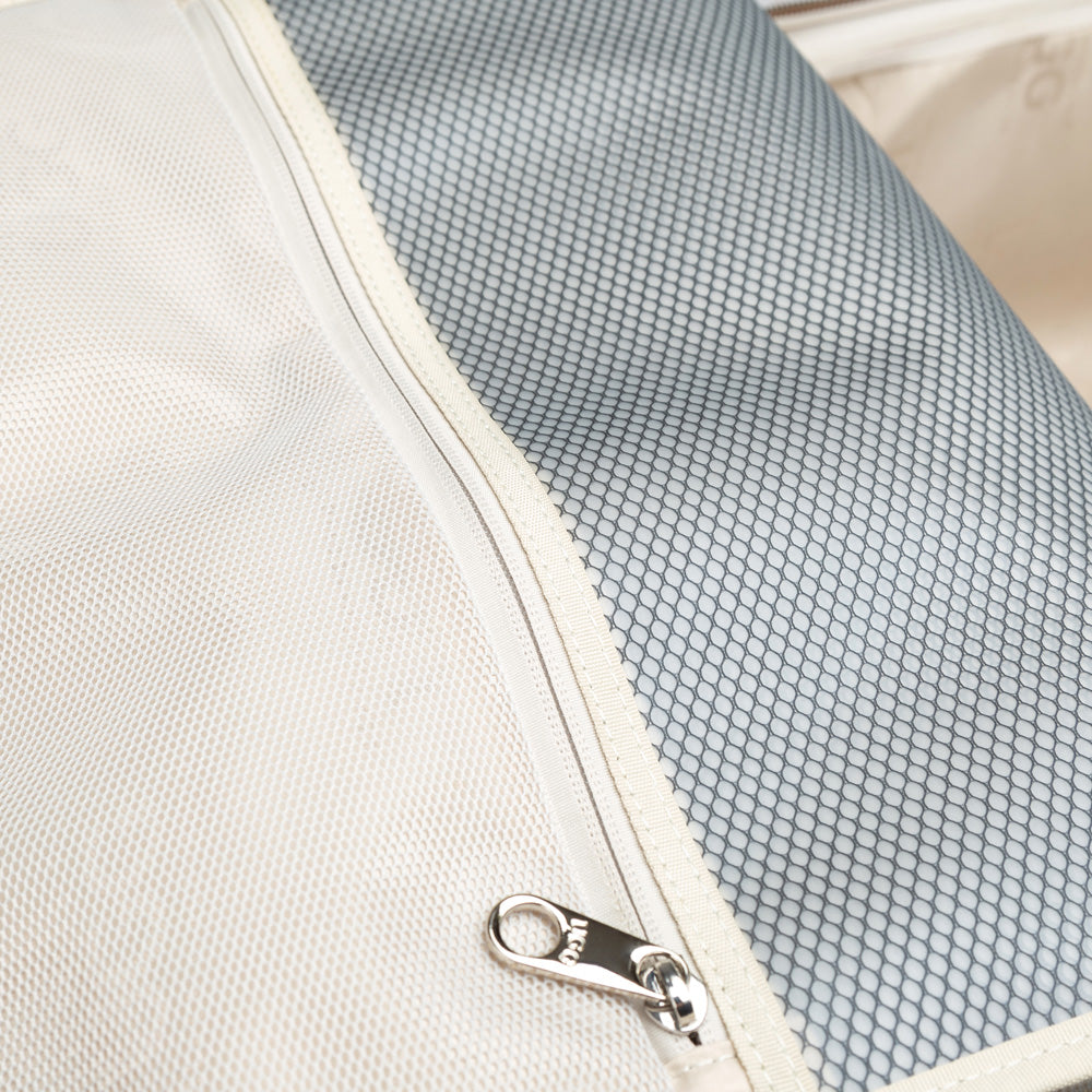 Close-up of a white and gray mesh pouch with a zipper in a UGG suitcase
