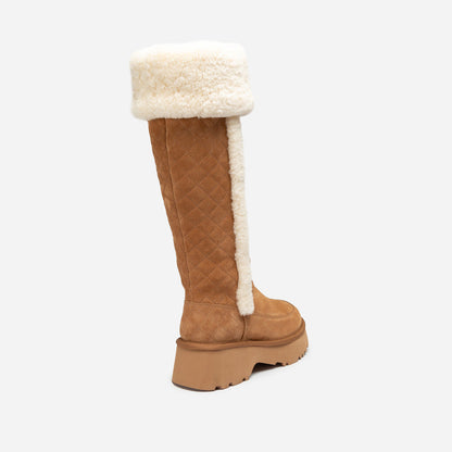 Tan knee-high UGG boot with white fur lining on a light gray background