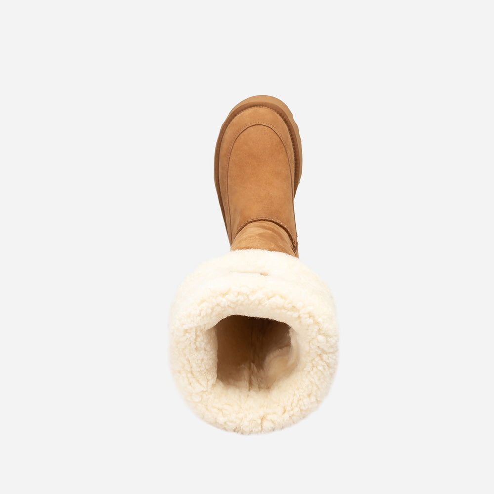 Brown suede UGG boot with white fur lining on a light gray background