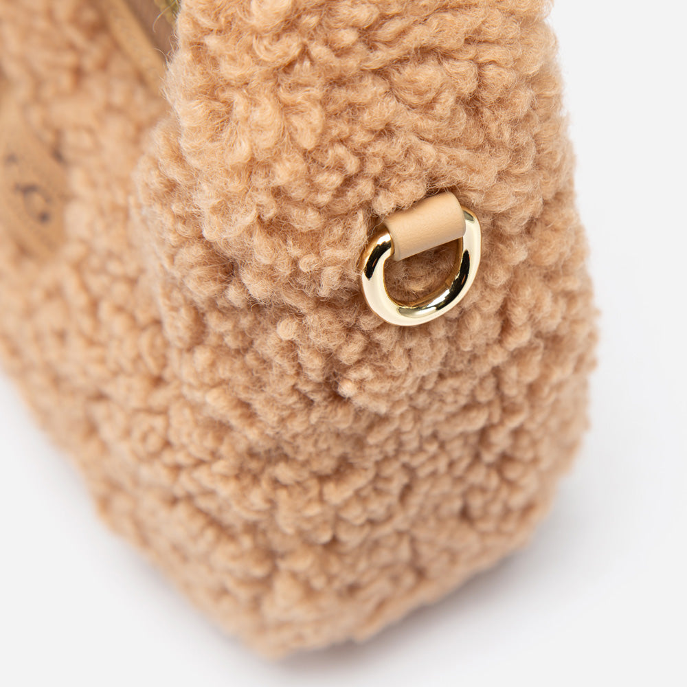 Close-up of a UGG shearling bag with a gold ring on a white background